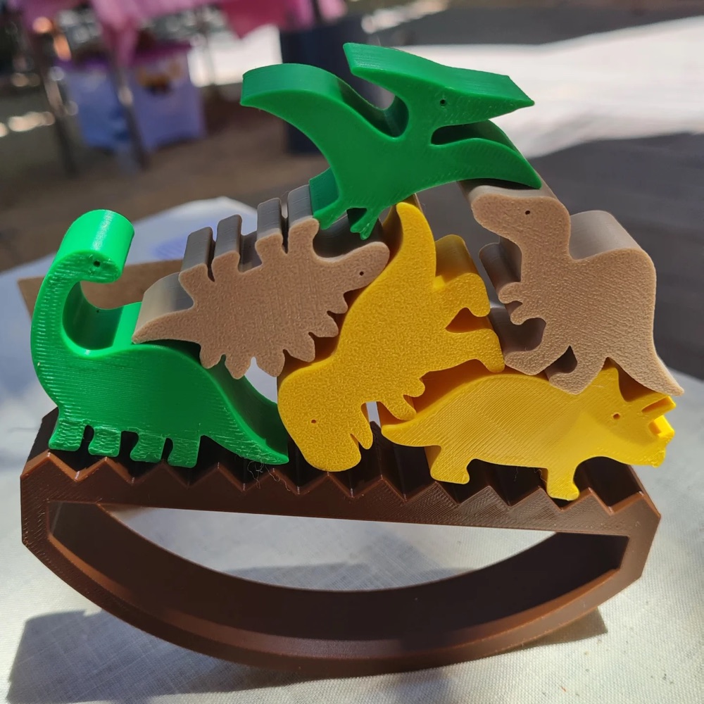 3D printed dinosaurs balancing on a wooden beam