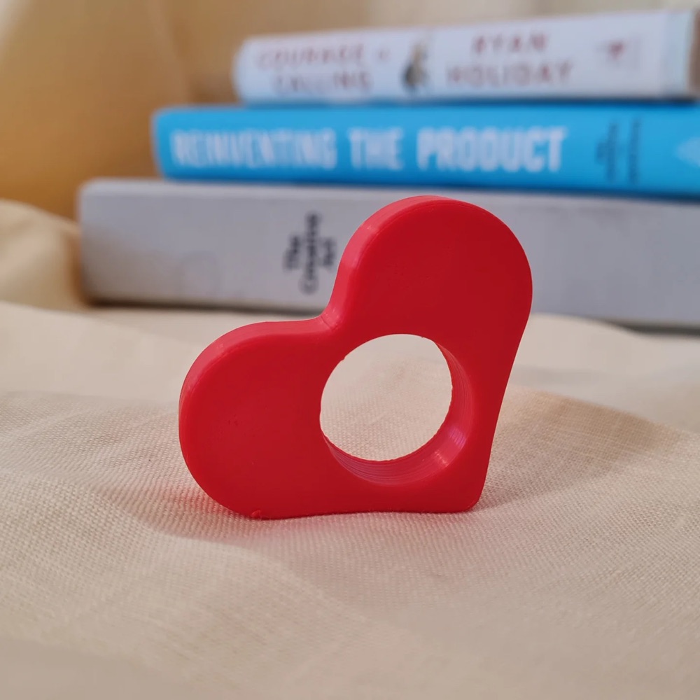 Red 3D printed heart resting on a stack of books